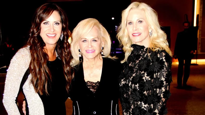 Three guests smiling for a photograph at a reception.