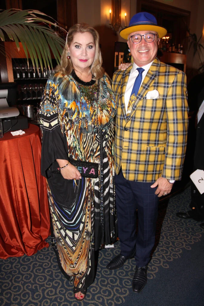 Two guests in colorful evening attire beside a cocktail reception table.