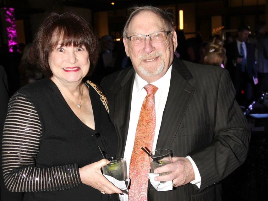 Two guests holding drinks at a reception.