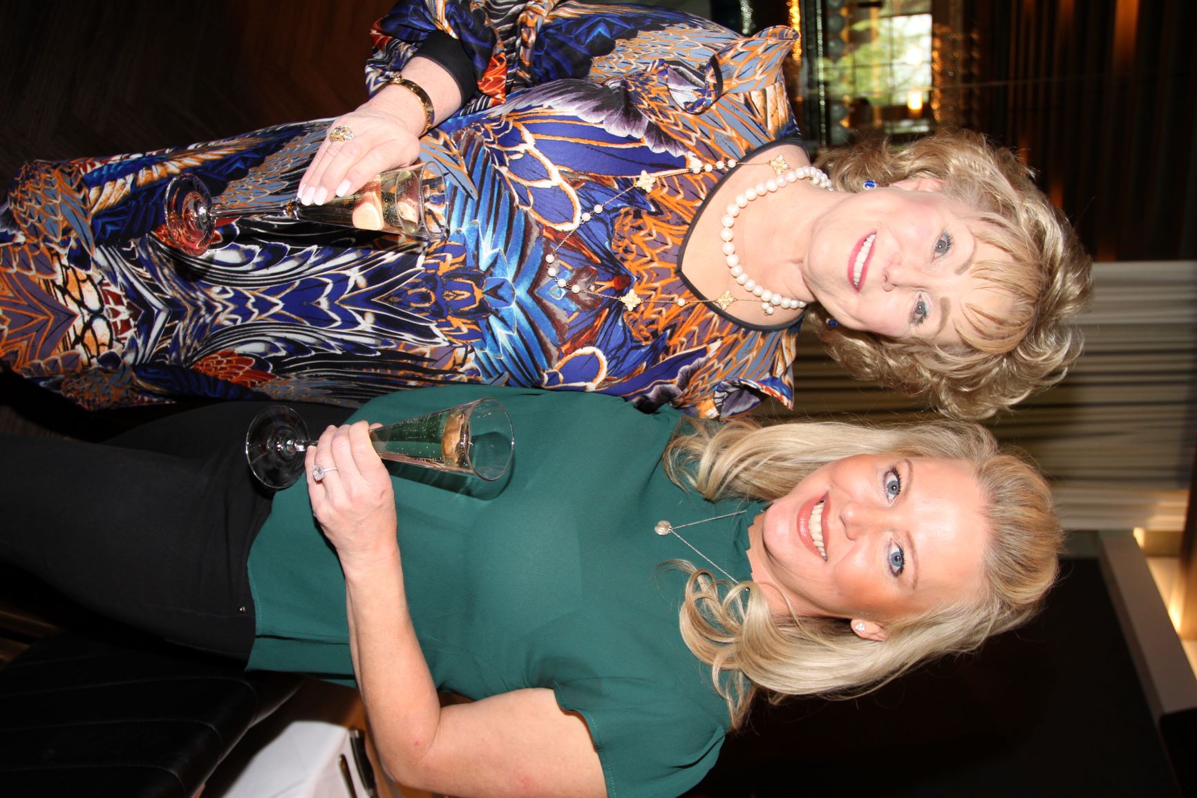 Two guests holding glasses and smiling at a daytime gathering.